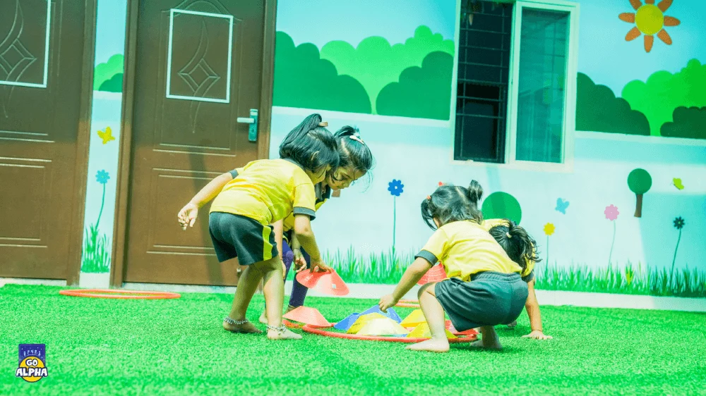Young girls in a Go Alpha preschool program in Pune develop balance and coordination using colorful stepping stones as part of their motor skills curriculum.